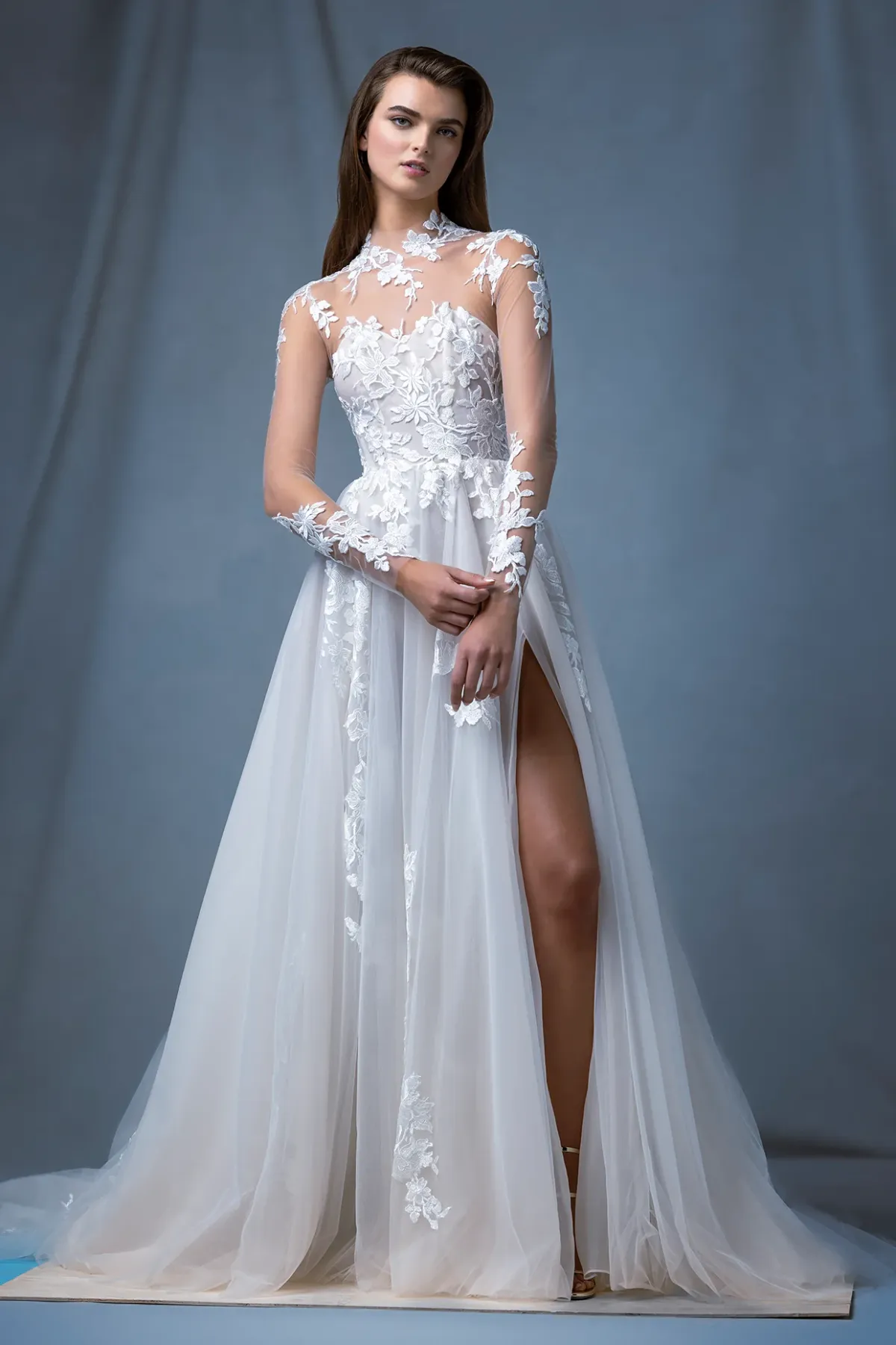 A model showcases the Ines Di Santo Ellipse dress while standing in a photography studio with gray backdrop