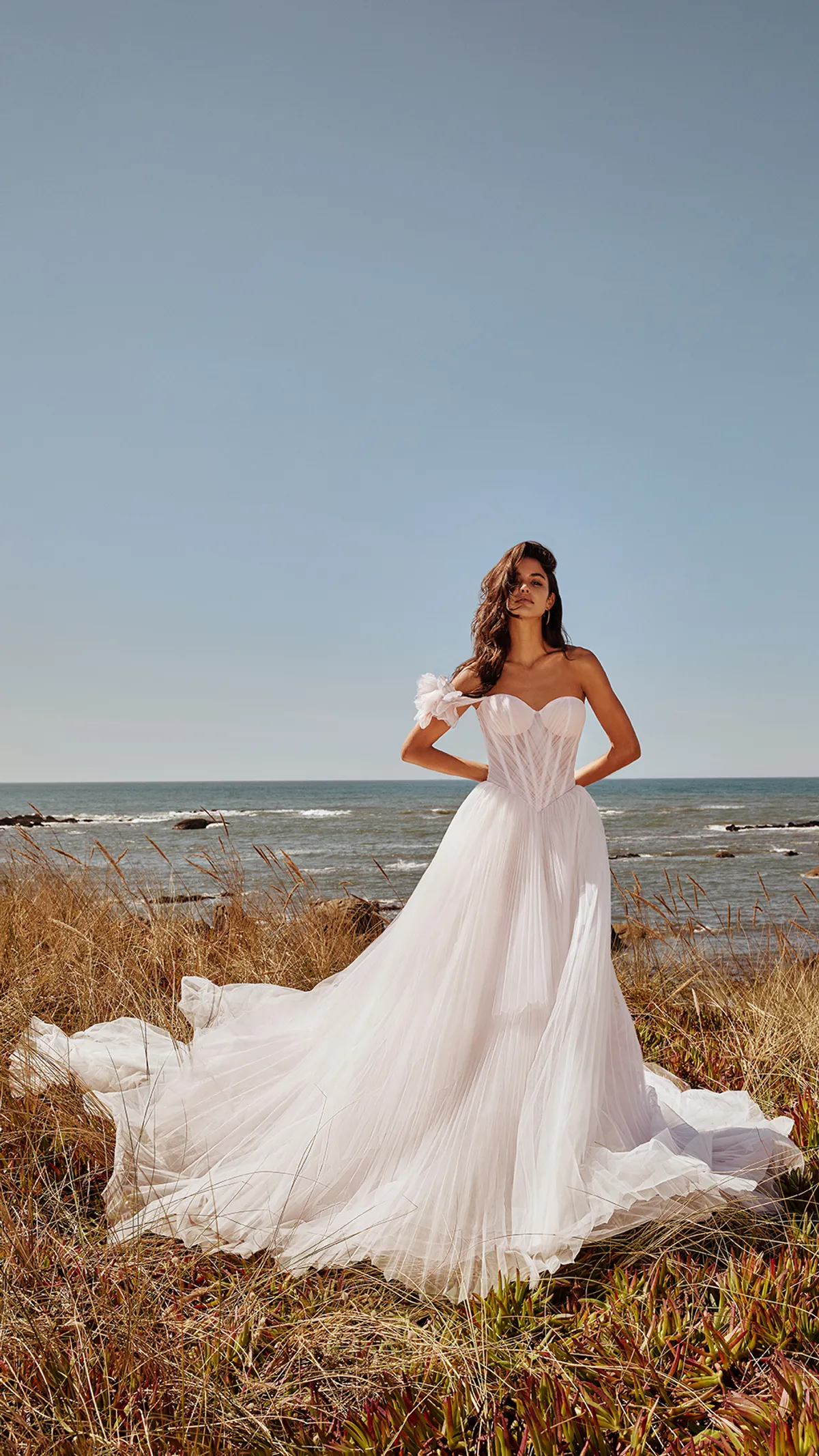 A model showcases the Galia Lahav fairytale dress near a beach