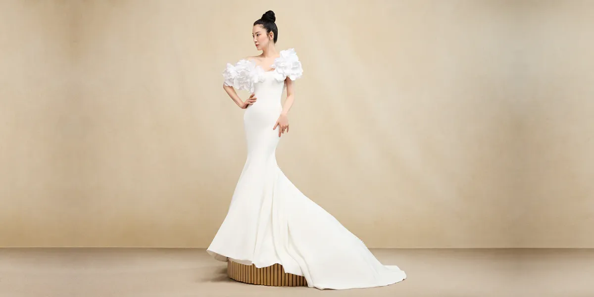 A model showcases the Ines Di Santo Motif dress while standing on a gold cirlce in a gold colored room