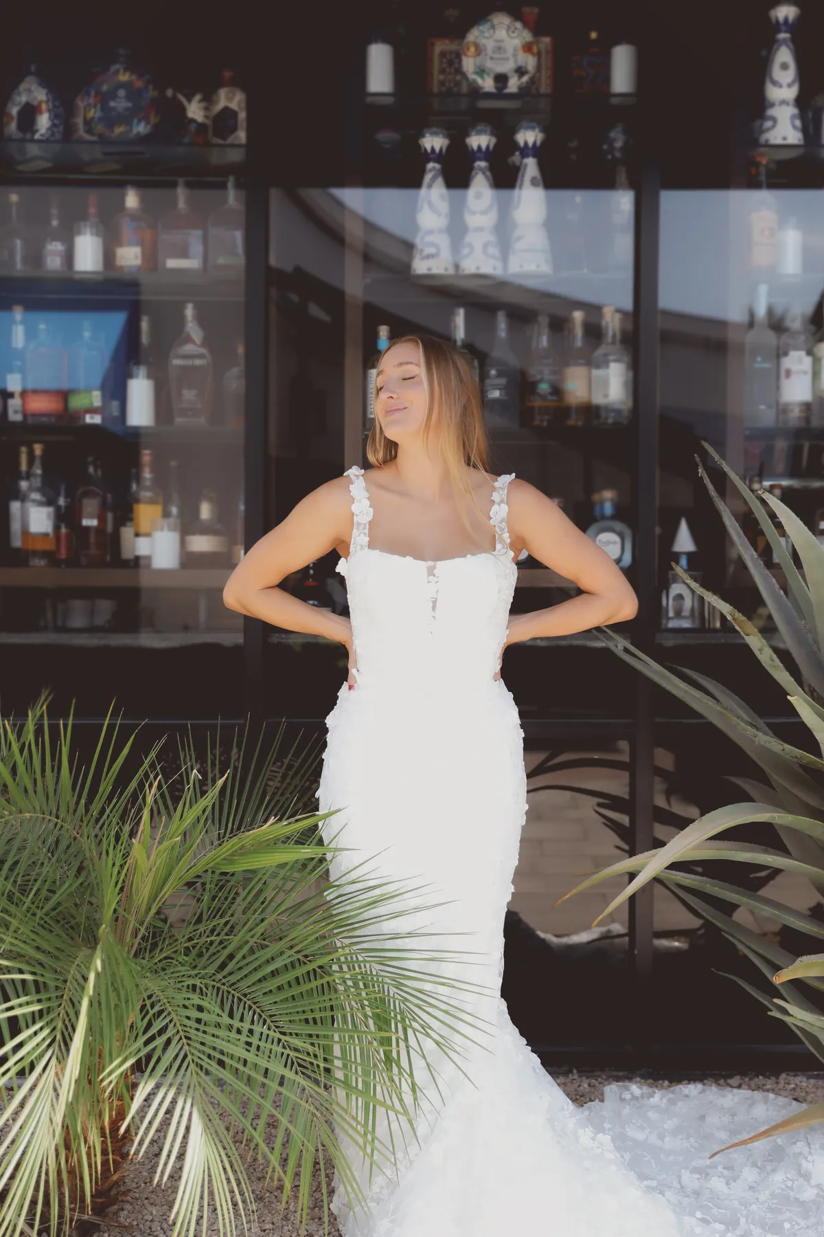 A model showcases the Angel Rivera Avery dress while standing in front of a window