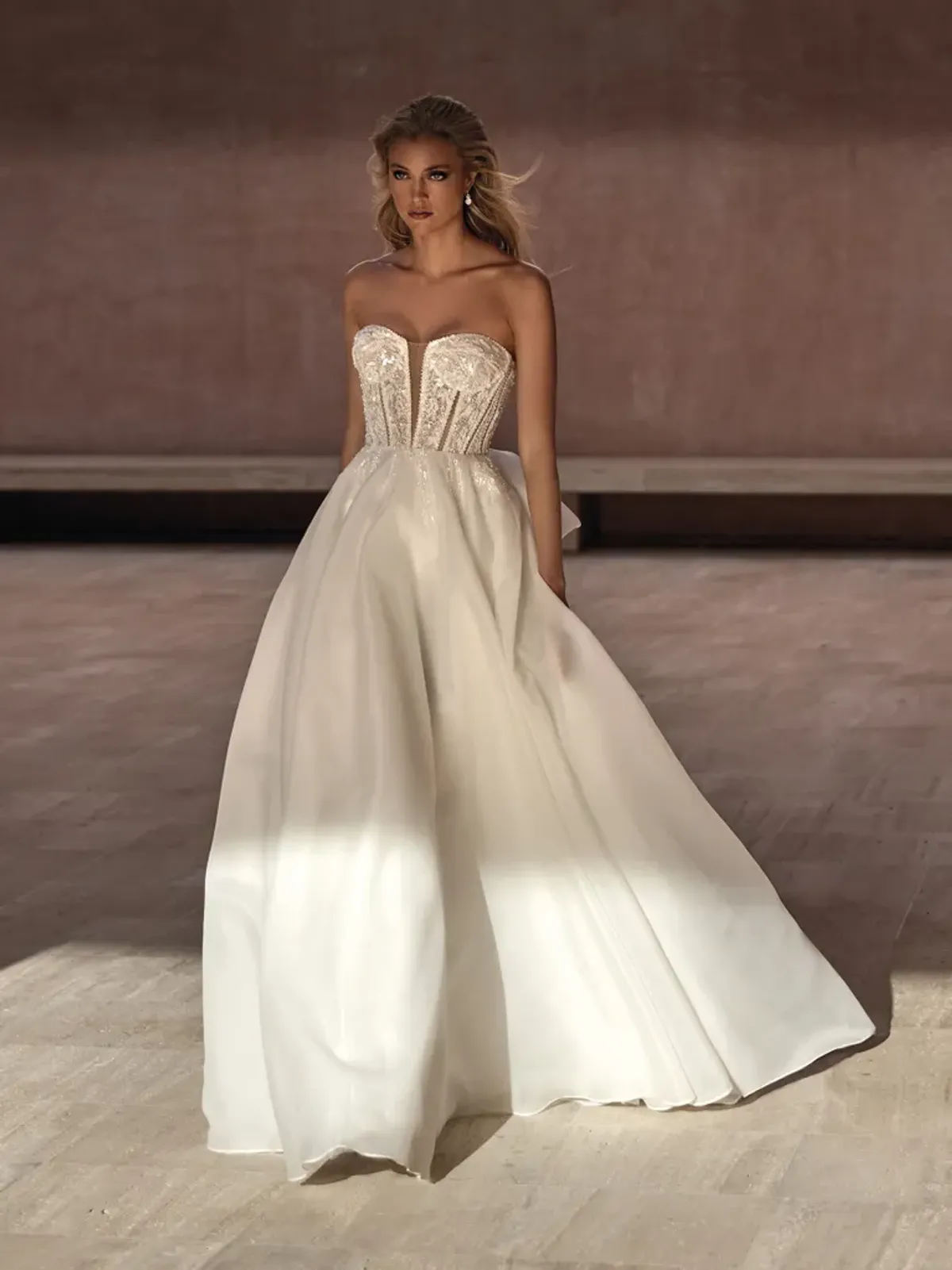 A model showcases the Pronovias Bayon dress in a large corridor