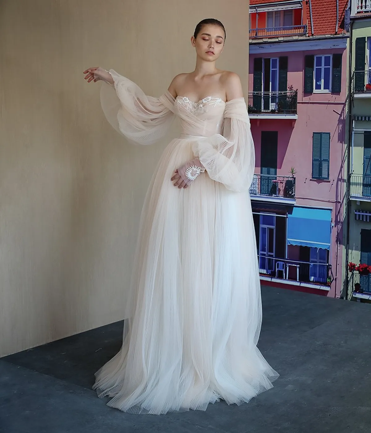A model showcases the Galia Lahav Bellina dress in a studio with a cityscape backdrop