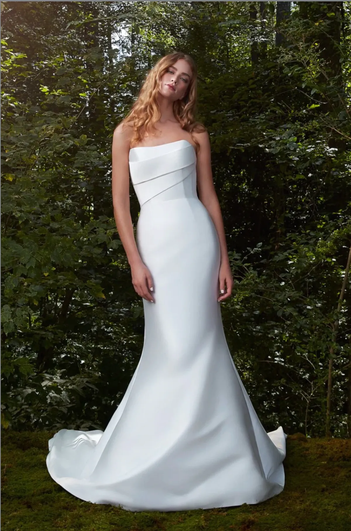 A model showcases the Anne Barge Bisous dress in a whimsical forest surrounded by trees