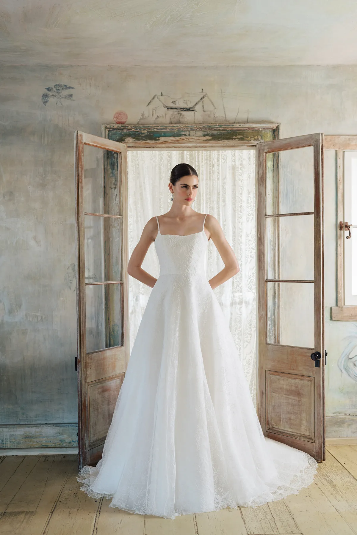 A model showcases the Anne Barge Brennen dress from the Blue Willow Bride collection in front of a doorway
