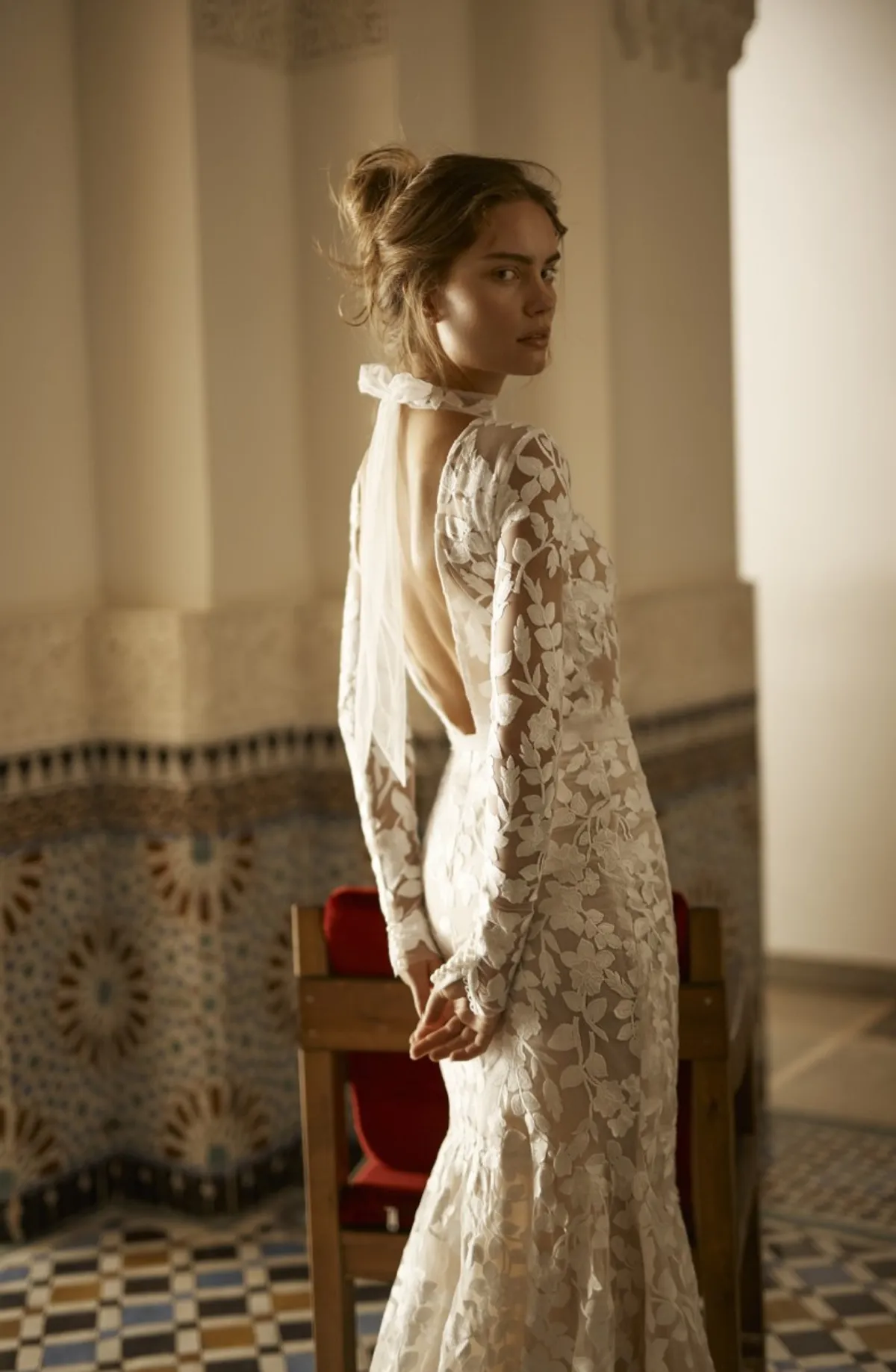 A model showcases the Arava Polak Brigitte dress in a tiled room