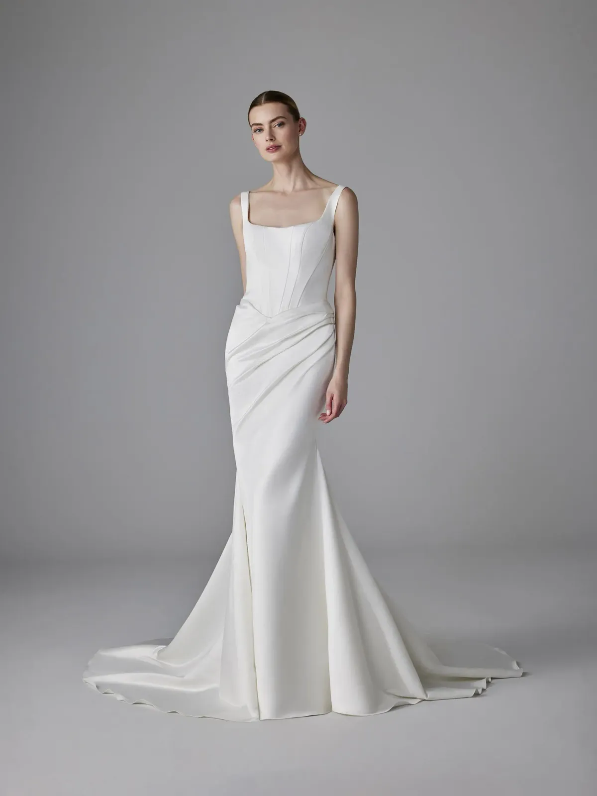 A model wears the Pronovias Dennise dress in a photography studio with white backdrop