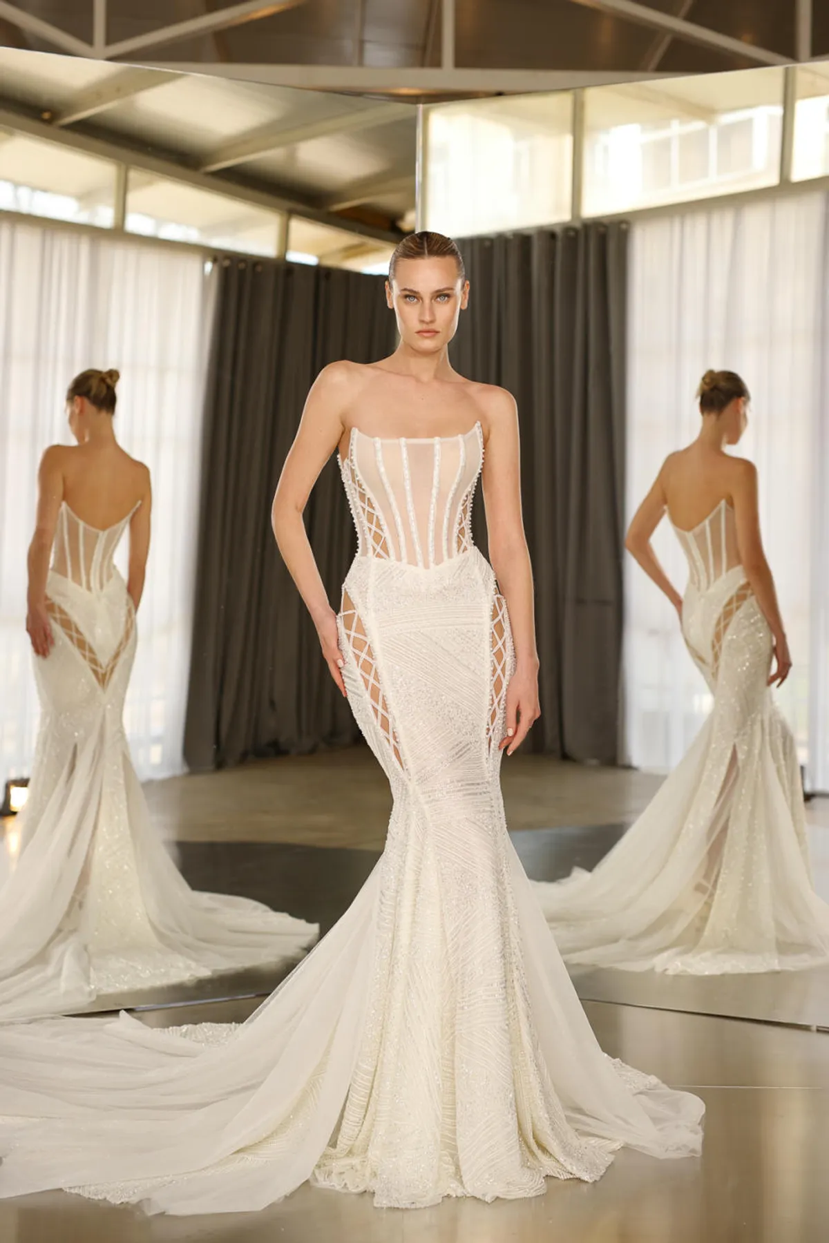 A model showcases the Galia Lahav Diem dress from the Couture collection in front of two angled mirrors inside a studio