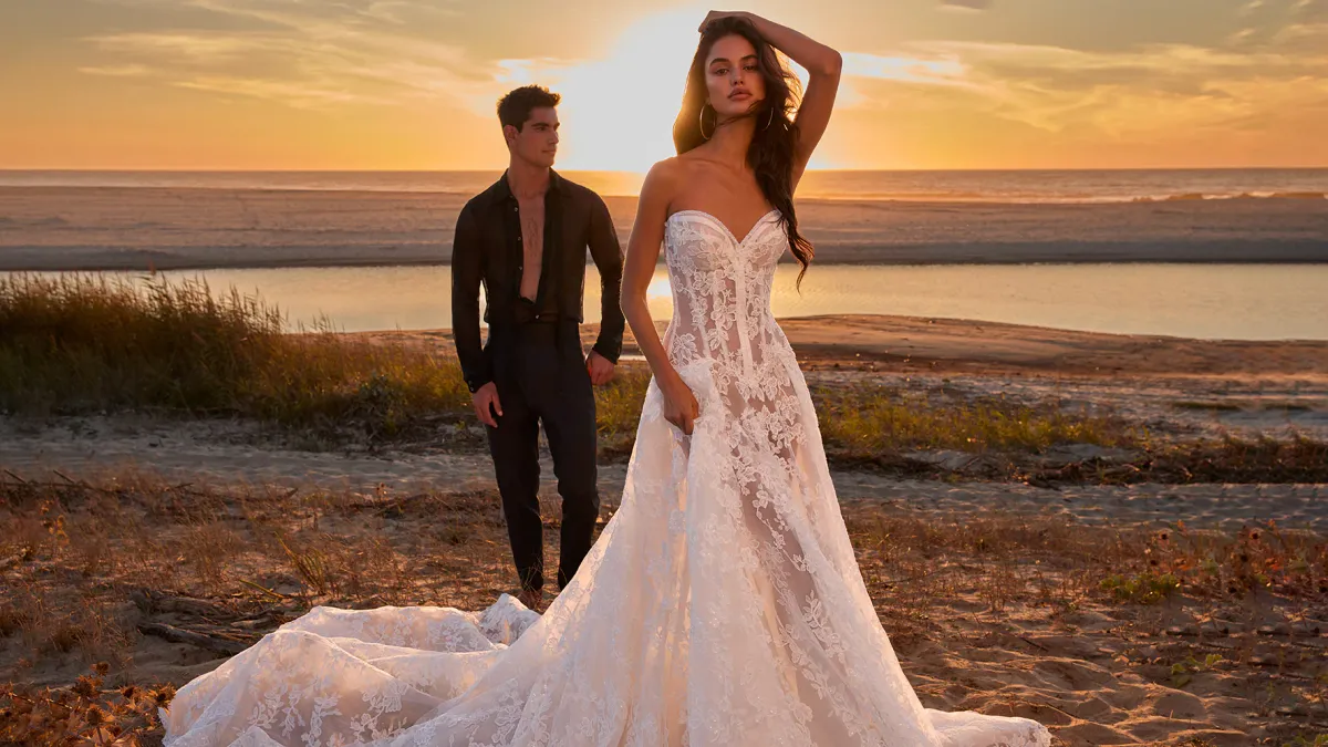 A husband and bride pose in front of a beach sunset