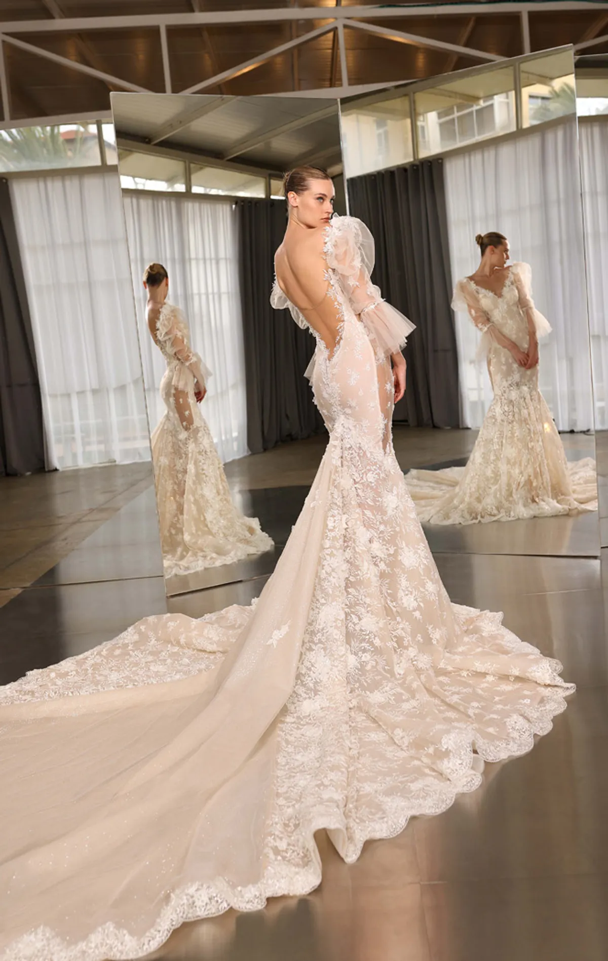 A model showcases the Galia Lahav Denise dress from the Couture collection in front of two angled mirros inside a studio