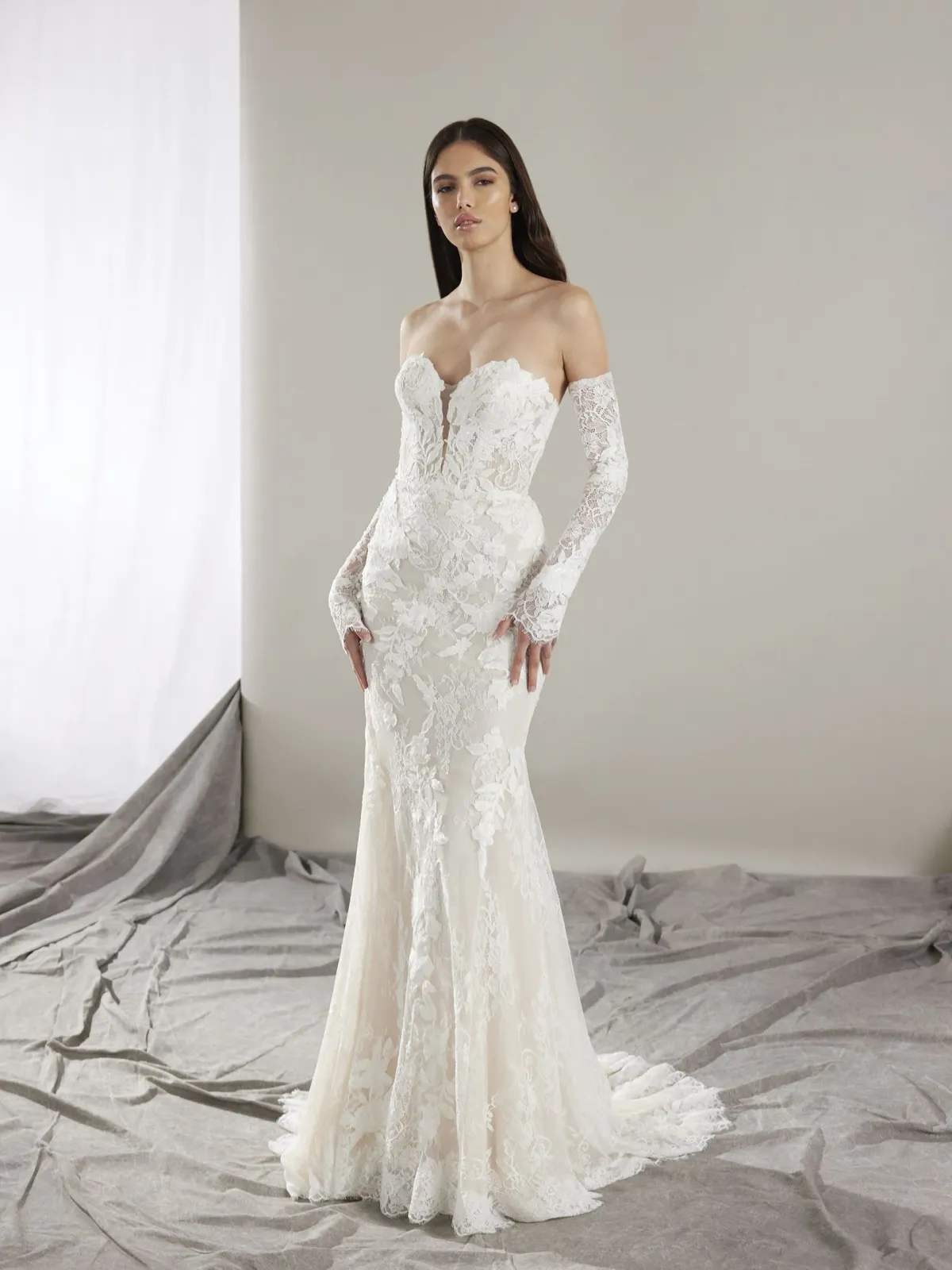 A model wears the Pronovias Hart dress in a photography studio with white backdrop