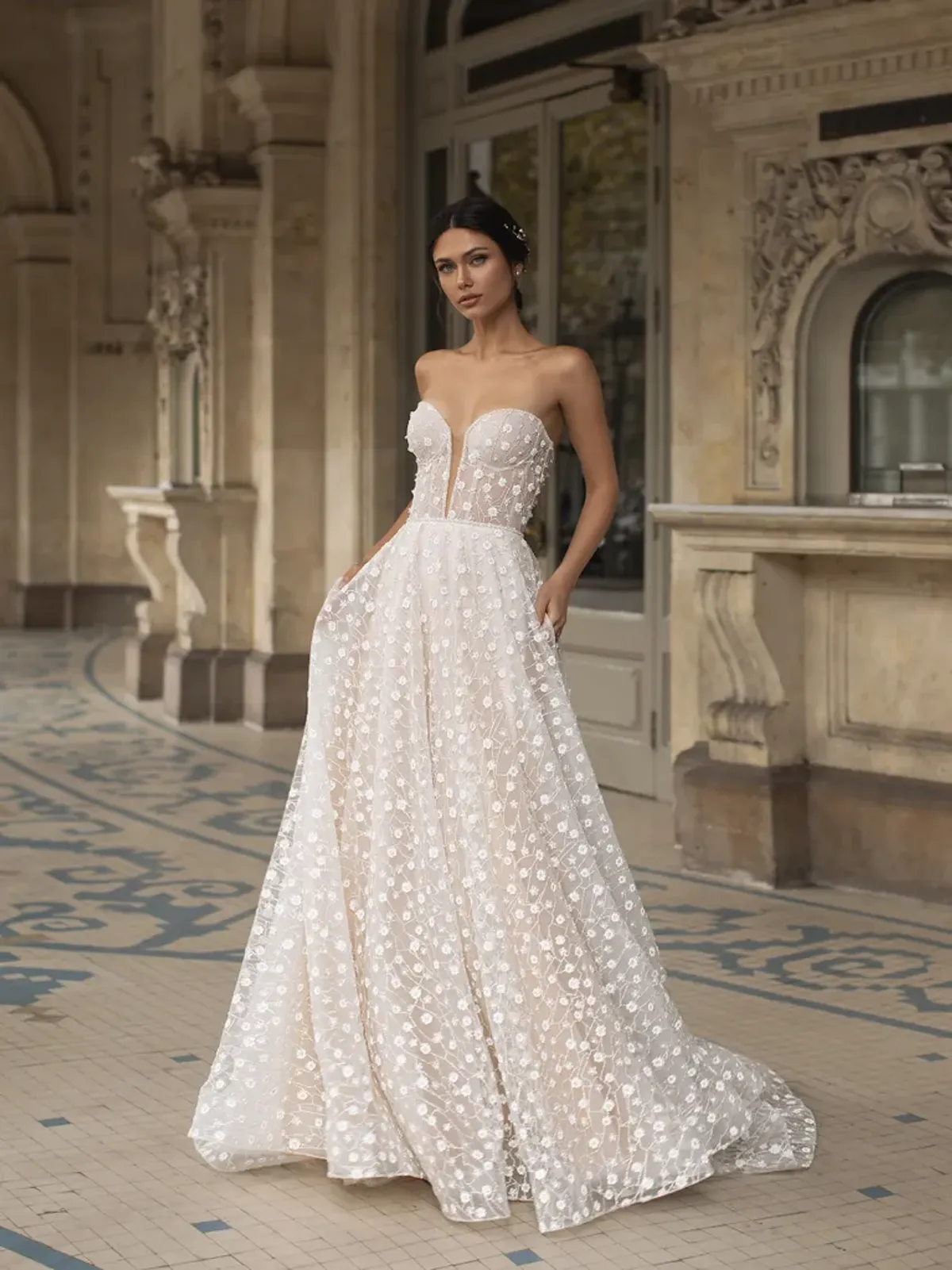 A model showcases the Pronovias Hopkins dress near an old European classically-styled building