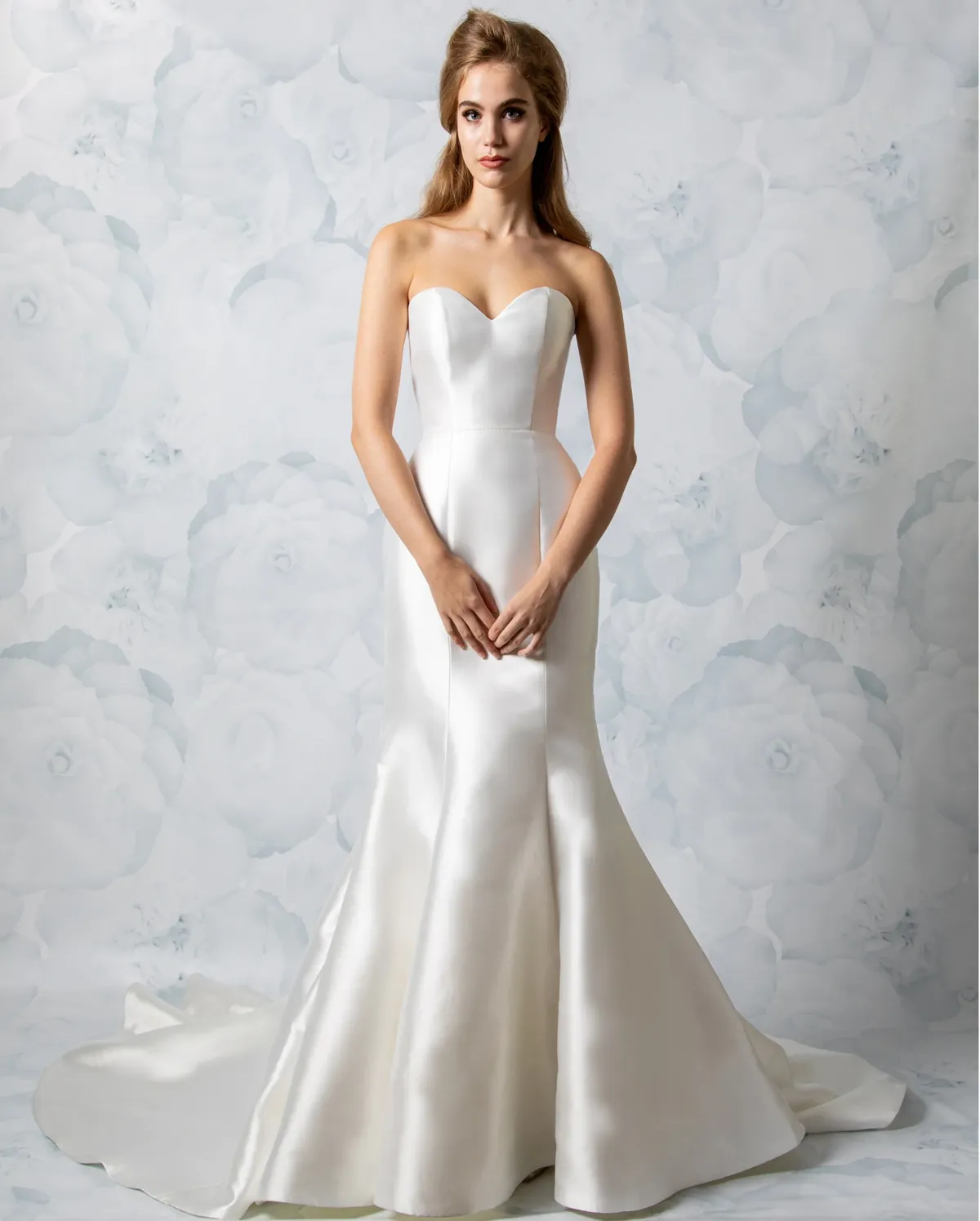 A model showcases the Antonio Gual Janet dress in a studio with floral blue-white backdrop
