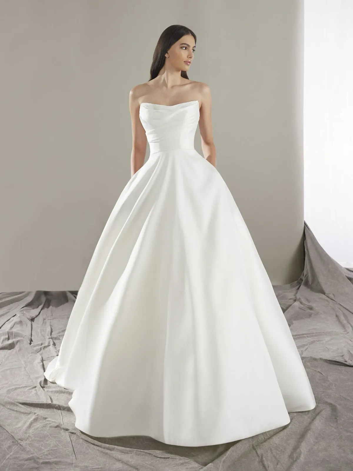 A model wears the Pronovias Keoni dress in a photography studio with a white backdrop