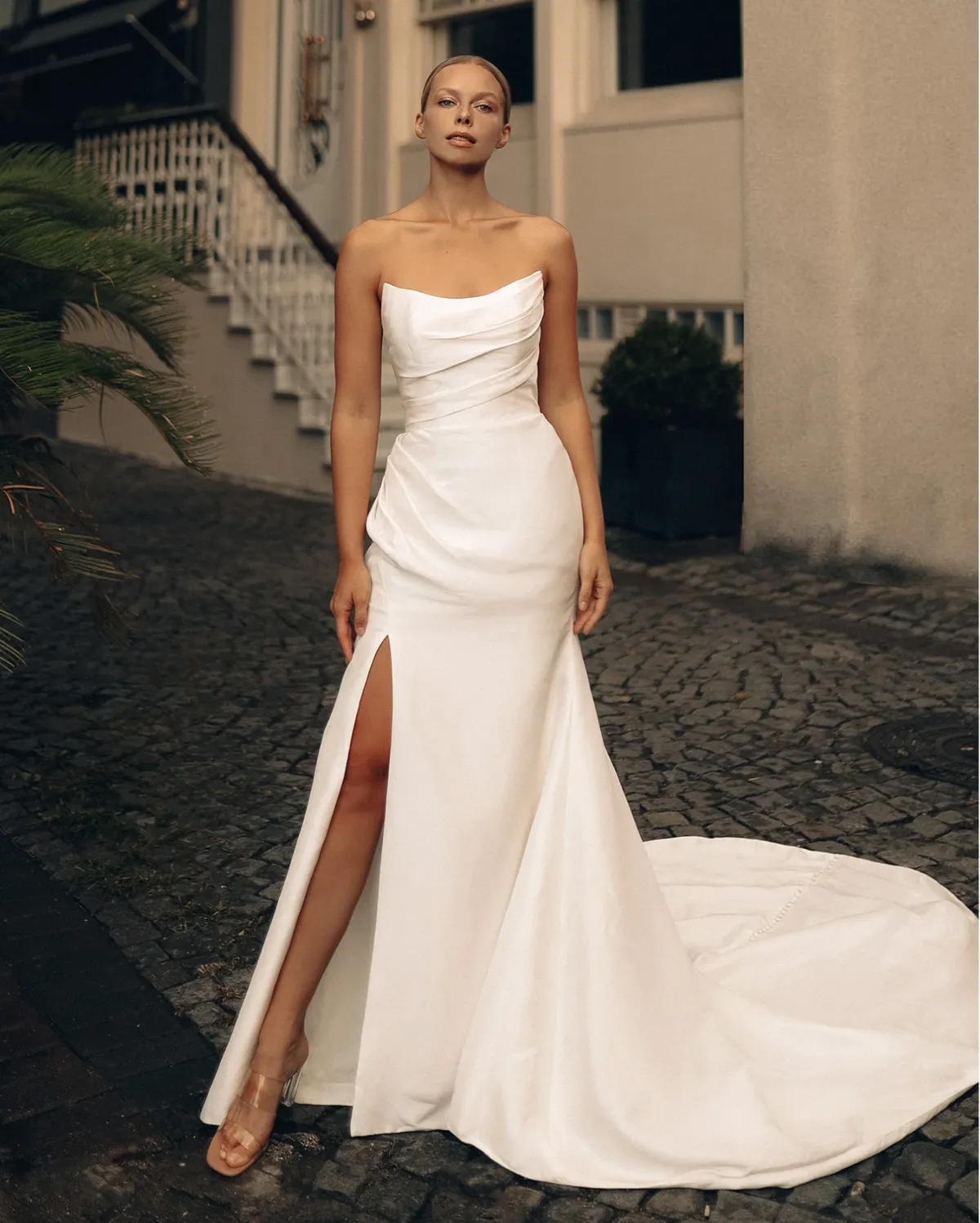 A model showcases the Antonio Gual LP dress near a cuban style house on a cobblestone streen during evening