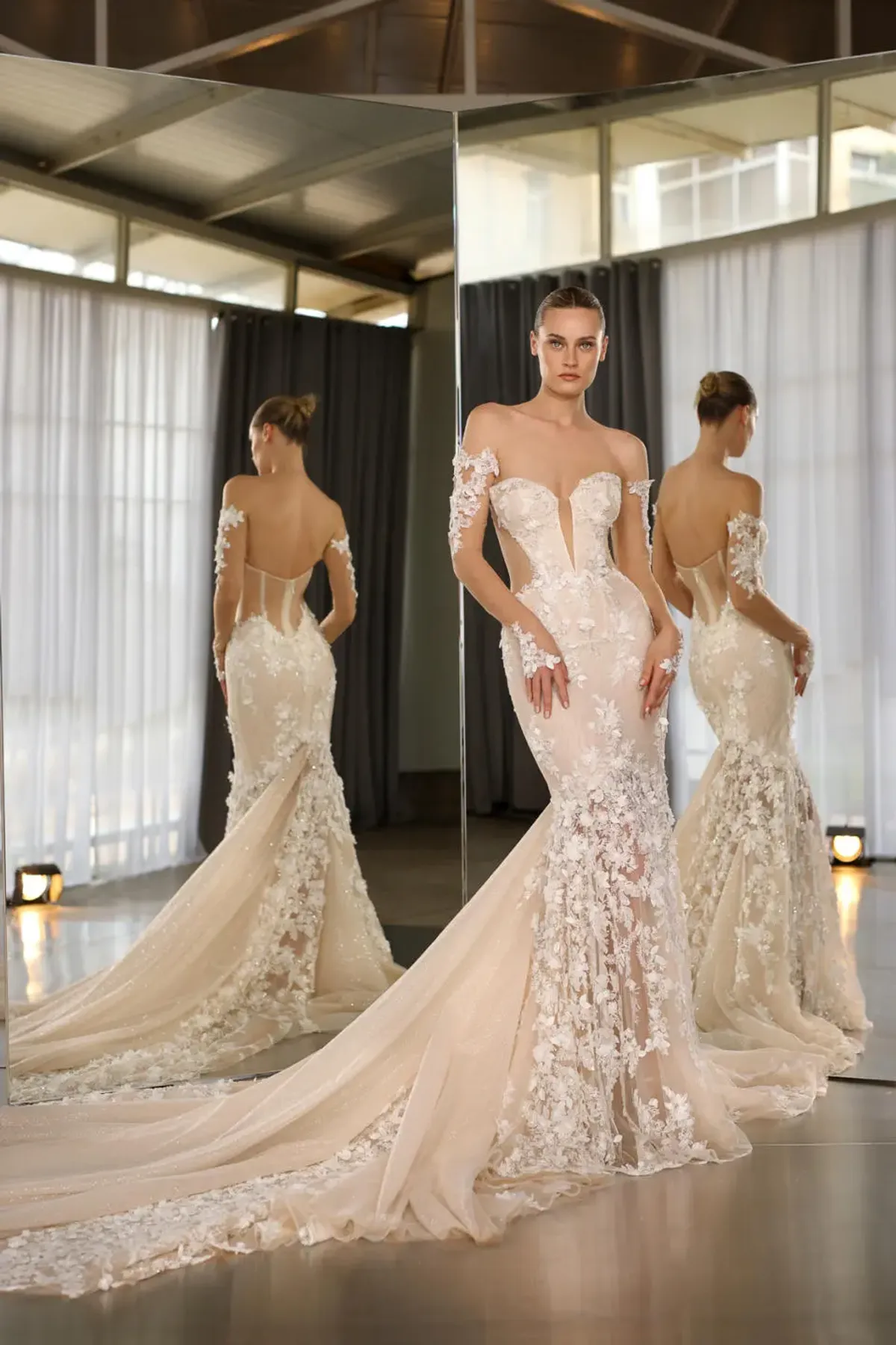 A model showcases the Galia Lahav Nadia dress from the Couture collection in front of two angled mirros inside a studio