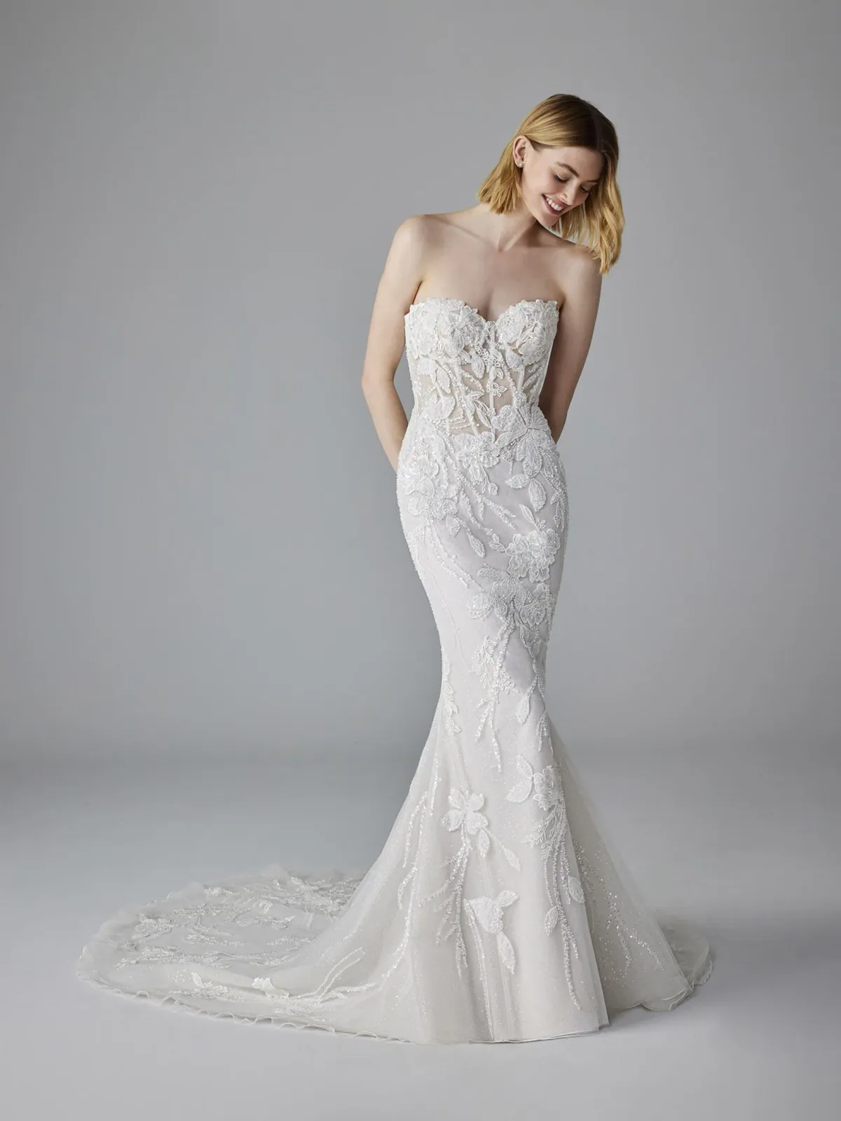 A model wears the Pronovias Nuage dress in a photography studio with white backdrop