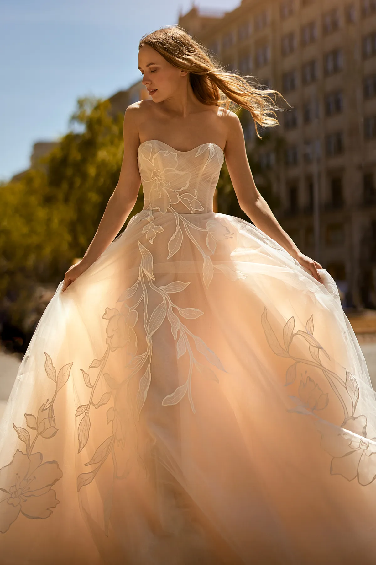 A model showcases the Ines Di Santo Rondo dress from the Ines by Ines Di Santo collection in front of a palace